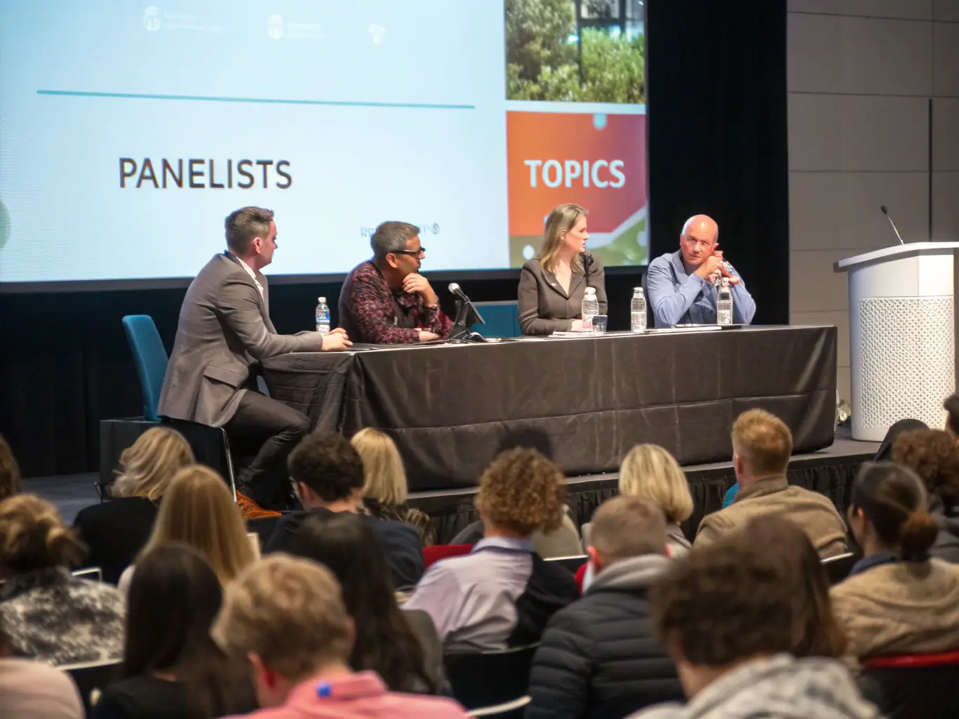 A photograph of a panel discussion featuring prominent business leaders at a BizConnect UK conference. The panelists are sharing insights and answering questions from the audience.